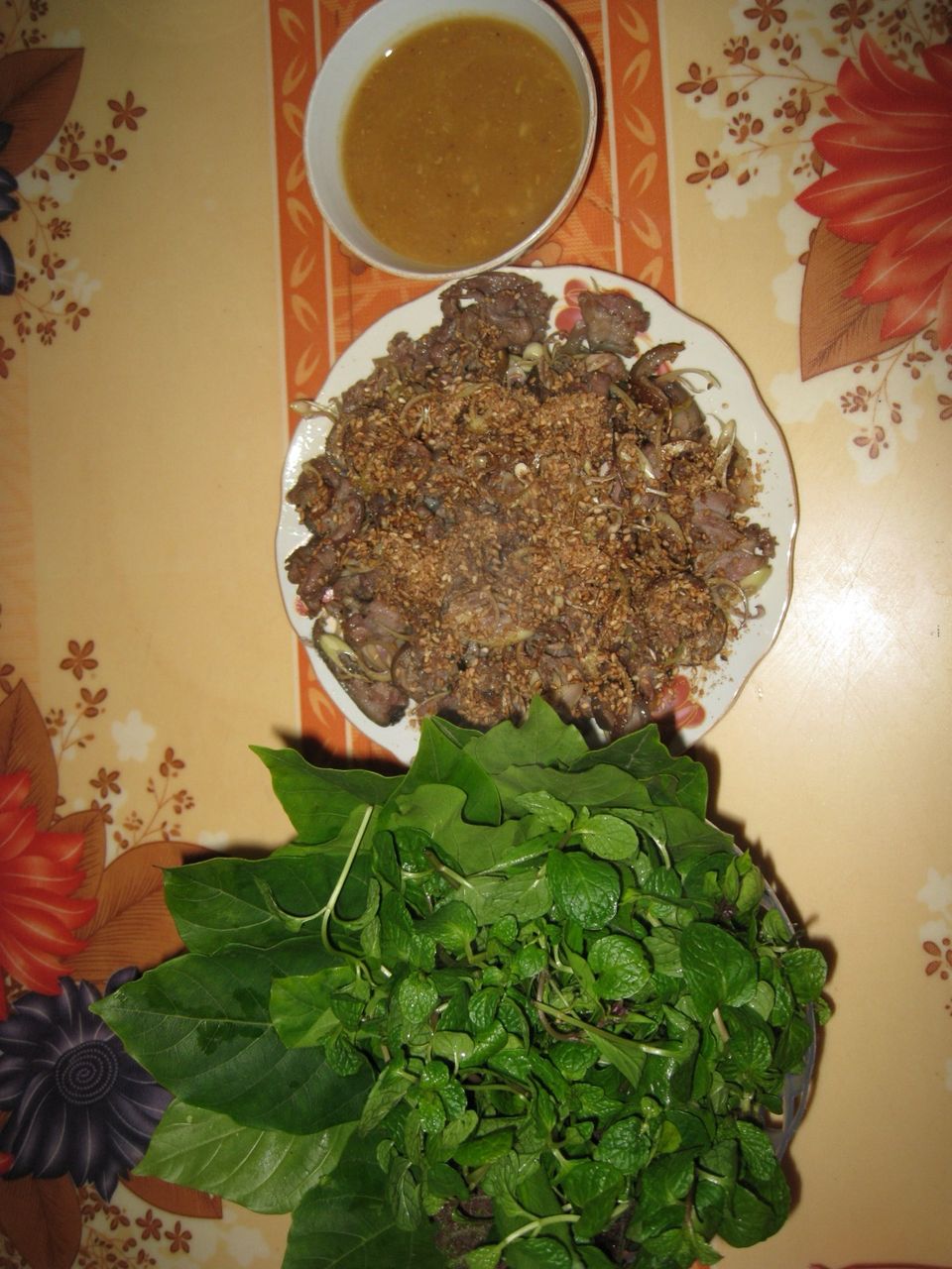 Đĩa dê tái rắc vừng, bát tương và rổ rau sống