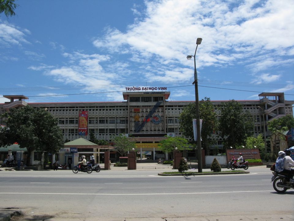Tòa nhà chính nhiều tầng của Trường Đại học Vinh nhìn từ đường lớn, trời xanh mây trắng